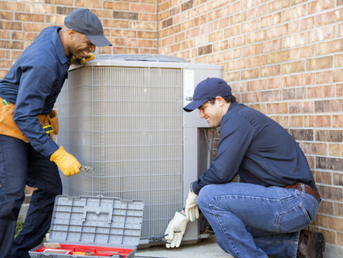 HVAC technicians installing condenser